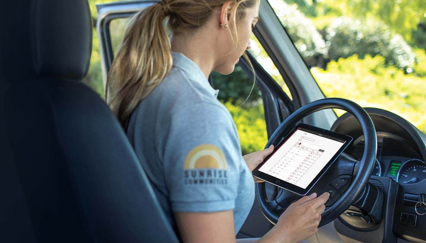 a woman is sitting in the driver's seat of a car using a tablet